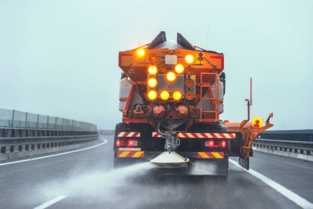 caminhão alaranjado do gritter da manutenção da estrada que espalha o sal da crosta de gelo na estrada no inverno. - snowplow snow blizzard truck - fotografias e filmes do acervo