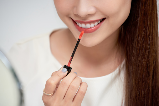 Young beautiful woman professional beauty vlogger or blogger applying lipstick cream to her mouth, doing a make up tutorial