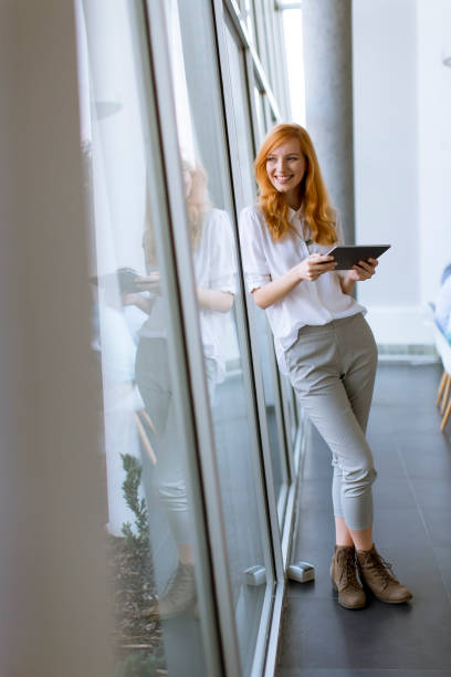 istock Pretty young red hair woman using digital tablet 1130067102