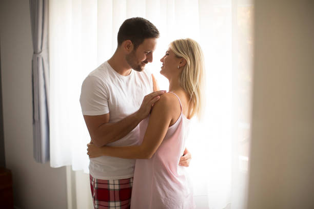 istock Romantic couple standing by window 1130067929