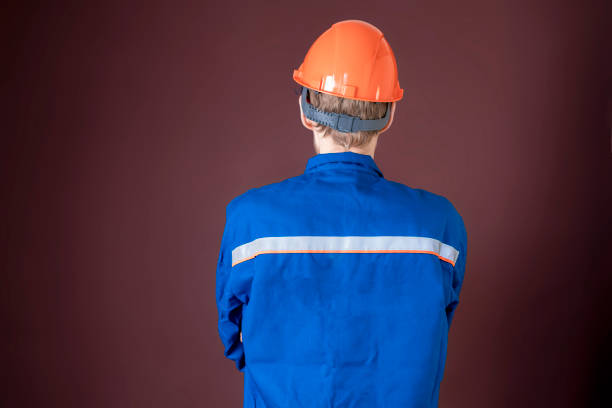 istock handyman in blue uniform and protective helmet isolated. back view b 1130068301
