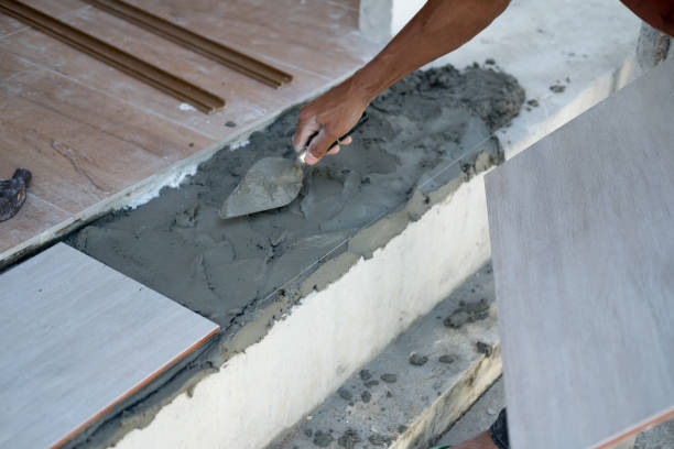 istock Construction worker with plaster knife for floor renovation.Tiler installing ceramic tiles on a floor. 1130069485