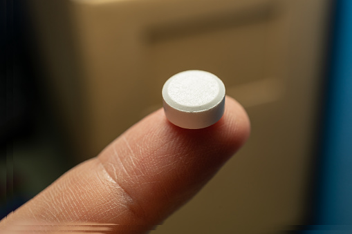 White Pill on Finger with blur background macro shot
