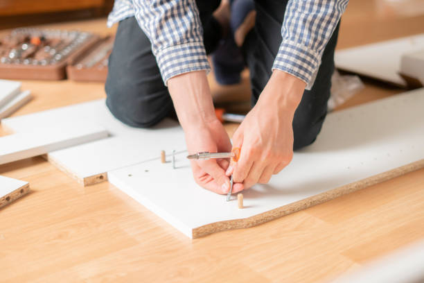 istock close up man assembling new furniture with a screwdriver b 1130073216