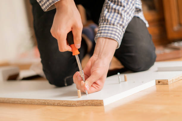 istock close up man assembling new furniture with a screwdriver b 1130073228