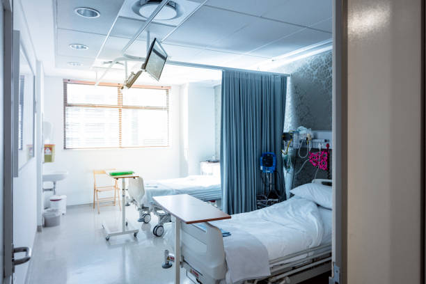 Interior of brightly lit empty hospital ward Interior of empty hospital ward. Curtain and medical equipment on bed. Sunlight streaming through window in room. hospital room stock pictures, royalty-free photos & images