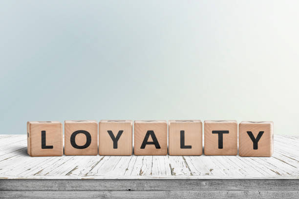 loyalität-schild an einem holztisch im hellen tageslicht - loyalität stock-fotos und bilder