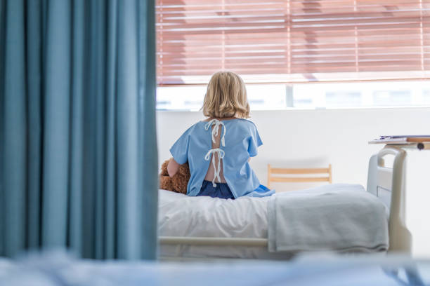 vista posteriore della ragazza malata seduta sul letto d'ospedale - rear view women back back of head foto e immagini stock