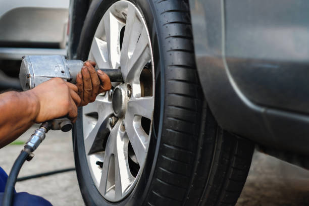 istock Tire Replacement concept. Mechanic Using Electric Screwdriver Wrench for Wheel Nuts in Garage. Car Maintenance and services 1130086456