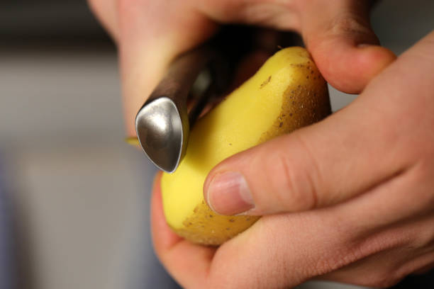 éplucher une pomme de terre crue avec éplucheur - raw potato organic human skin food photos et images de collection