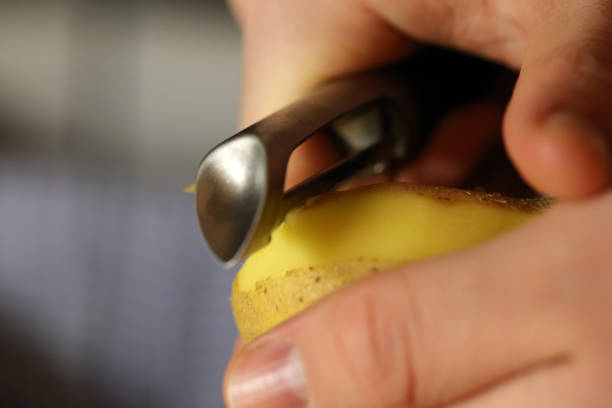 пилинг сырой картофель с картофелем пилер - raw potato organic human skin food стоковые фото и изображения