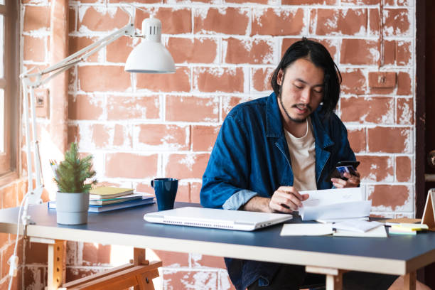 istock young smart asian creative designer start new project at loft interior studio with tool laptop and stationary stuff 1130099511