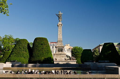 This is a picture of center part of Ruse in Bulgaria, in the background is the city court and the Monument of Freedom, in the foreground there is a park.