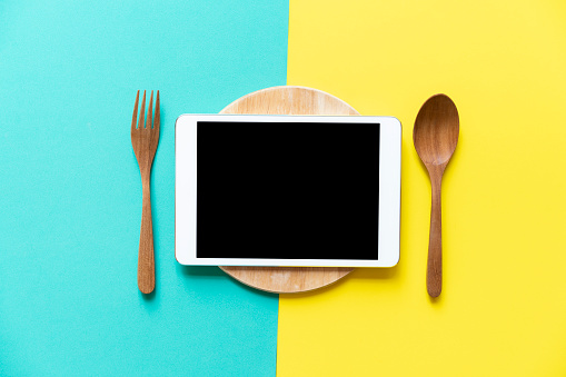tablet device served on colourful table background, food and menu concept and idea