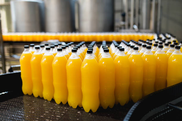 Bottling plant Bottling factory - Orange juice bottling line for processing and bottling juice into bottles. Selective focus. industrial orange stock pictures, royalty-free photos & images