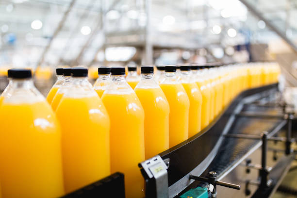 Bottling plant Bottling factory - Orange juice bottling line for processing and bottling juice into bottles. Selective focus. non alcoholic beverage stock pictures, royalty-free photos & images