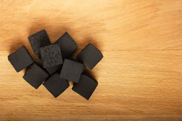 Photo of Coconut coals for hookah cubes on wooden background