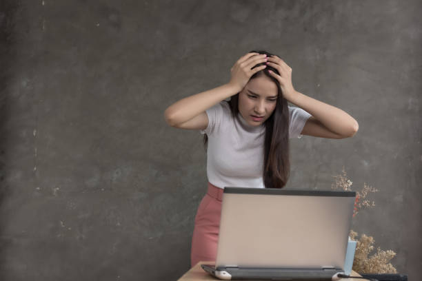 istock Business woman work in office and using laptop computer ,study business ideas.report finance,sales summary document on table.Hand hold head look serious and headache 1130110388