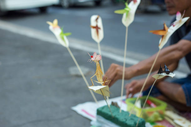 Bangkok, THAILAND - February 9, 2019: People who make handcraft, folding colourful fake insects make with palm leafed at wayside for sale to tourist.