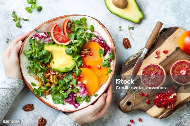 Vegan Detox Buddha Bowl With Turmeric Roasted Chickpeas Greens Avocado Persimmon Blood Orange Nuts And Pomegranate Top View Flat Lay Stock Photo - Download Image Now