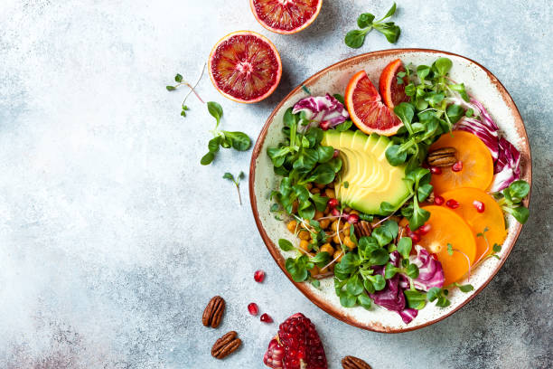Vegan, detox Buddha bowl with turmeric roasted  chickpeas, greens, avocado, persimmon, blood orange, nuts and pomegranate. Top view, flat lay stock photo