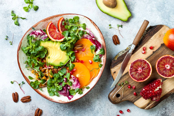 vegano, disintossica la ciotola del buddha con ceci arrostiti alla curcuma, verdure, avocado, cachi, arancia rossa, noci e melograno. vista dall'alto, lay piatto - pomegranate fruit tropical fruit freshness foto e immagini stock