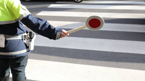 policeman with the paddle to stop the car on the pedestrian cros policeman with the paddle to stop the car on the pedestrian crossing traffic fine stock pictures, royalty-free photos & images