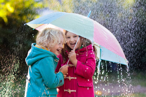 istock Kids with umbrella playing in autumn shower rain. 1130116132