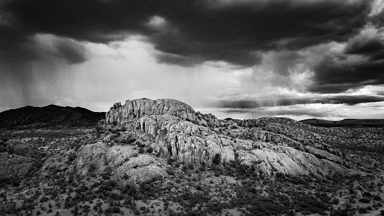 Aerial View of Dramatic Landscape Scene with sunlit Rock Formation and Thunderstorm Clouds in the Background. Drone Point of View. Edited Black and White Panorama. Windhoek - Rehoboth Region, Namibia, Africa