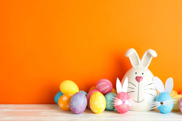 istock Decorated bunny and Easter eggs on table against color background. Space for text 1130125290