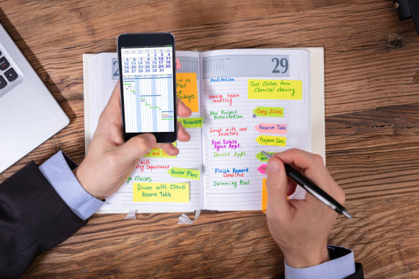 istock Businessman Holding Cellphone Writing Schedule In Diary With Pen 1130134976