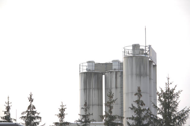 istock Tower of a cement plant with trees in the front 1130138173