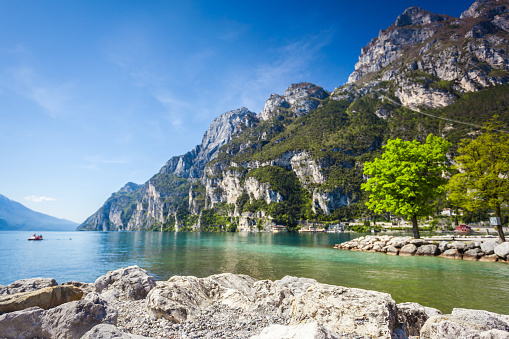 Beautiful defocused coast of Riva del Garda in Italy. Focus on the stones on the foreground