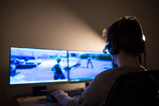 jeune garçon jouant des jeux sur un ordinateur à la maison - blank expression audio photos et images de collection