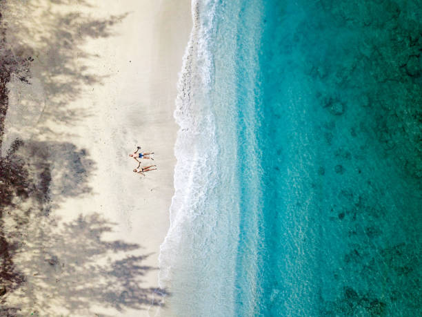 インドネシアのビーチでリラックスした若いカップルの航空写真 - 仰向きに寝る ストックフォトと画像