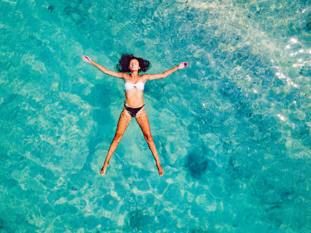 Underwater - Follow me concept woman leading boyfriend on idyllic beach in pristine clear water in the Islands of Thailand. People travel destinations concept