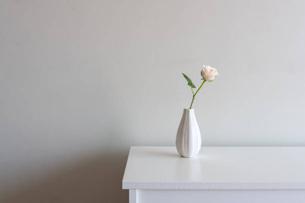 istock Pale pink rose in small vase on white sideboard 1130152269