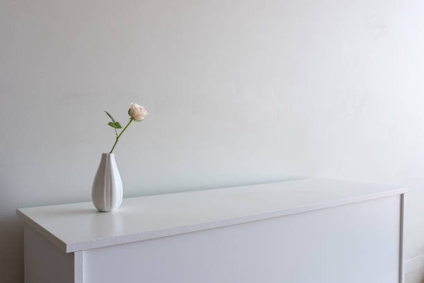 istock Single pale pink rose in vase on white sideboard 1130153380