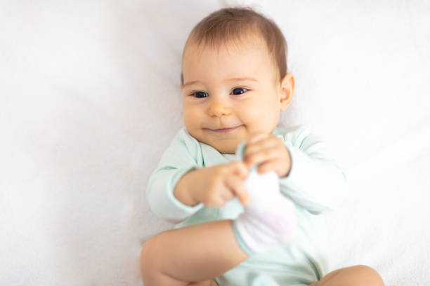 istock Cute baby playing with her legs on the bed 1130169035