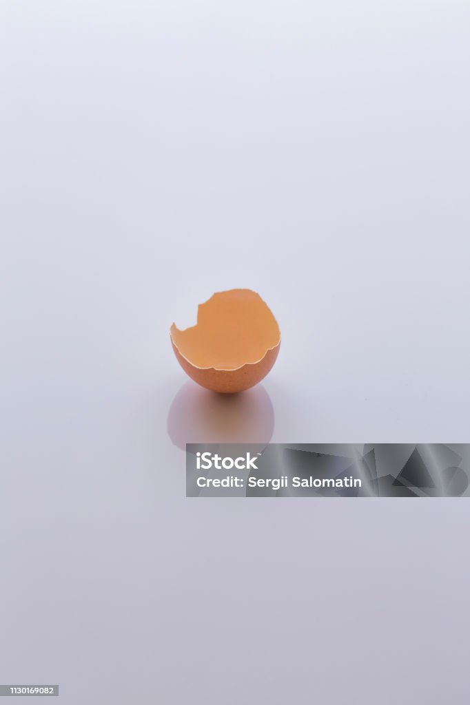 Broken raw egg without yellow yolk (empty, shell only) on a bright white glossy surface (background) of the kitchen table Animal Stock Photo