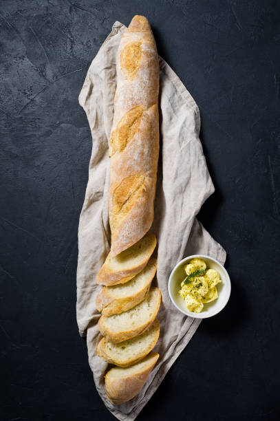 istock French baguette and butter. Black background, top view. 1130176981