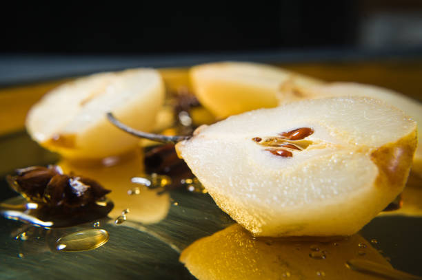 istock Sliced pear poached on a gold tray, cooked on white wine. Black background, side view, close up. 1130177162