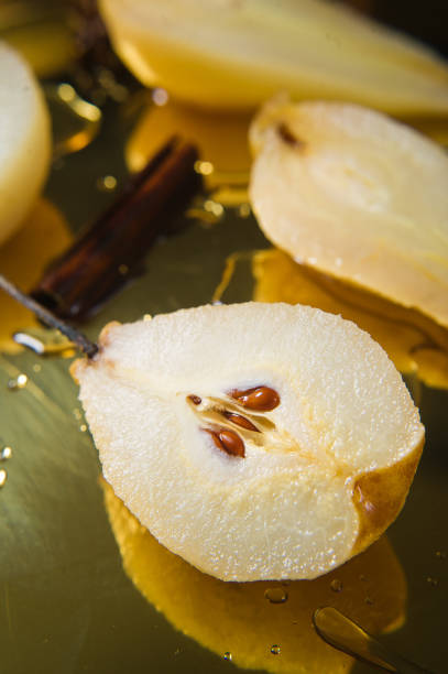 istock Sliced pear poached on a gold tray, cooked on white wine. Black background, side view, close up. 1130177181