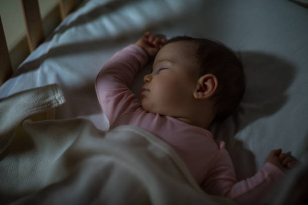Baby Sleeping on the bed Adorable baby sleeping at night. Little girl in pajama taking a nap in room with toy. baby sleeping bedding bed stock pictures, royalty-free photos & images