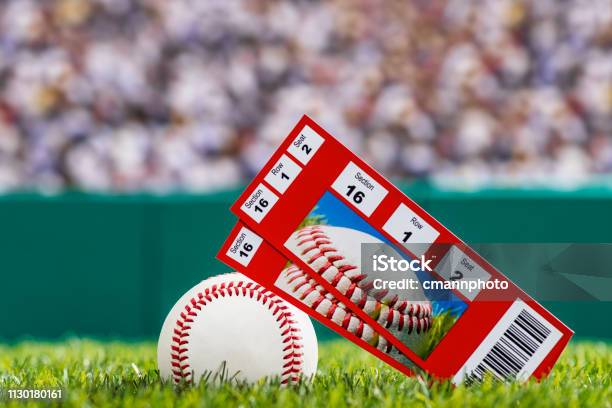 A Pair Of Ticket Stubs Sitting On A Baseball In The Grass Of A Stadium Stock Photo - Download Image Now