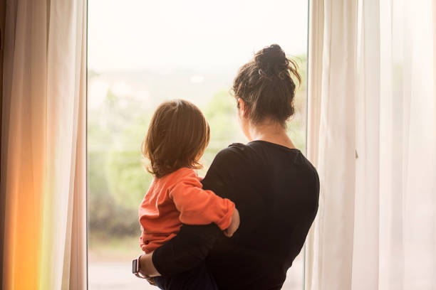 mère et fils regarde par la fenêtre - mère photos et images de collection