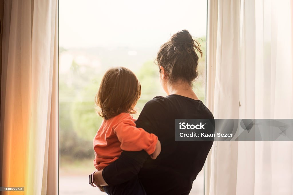 Mother and son looking out of window Child Stock Photo