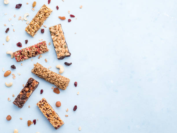 conjunto de barritas diversas sobre fondo azul - protein bar cereal oat cranberry fotografías e imágenes de stock