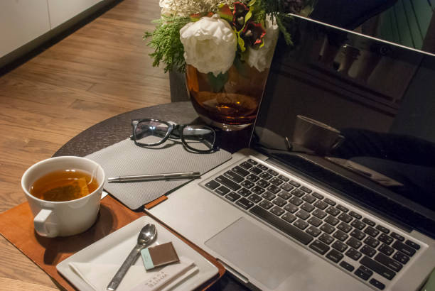 istock White tea cup on a wooden desk With a rose vase placed Open the laptop and work 1130187830