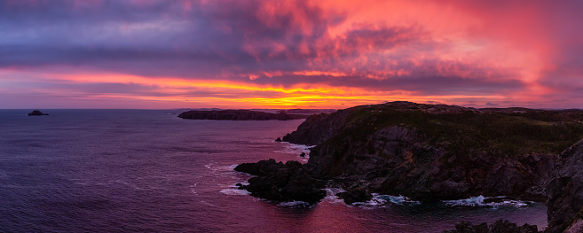 Striking panoramic seascape view on a rocky Atlantic Ocean Coast during a colorful sunrise. Taken at Crow Head, North Twillingate Island, Newfoundland and Labrador, Canada.
